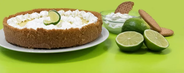 Key lime pie with cookies and lime on a green background