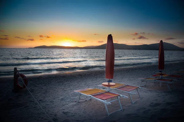 Beach chairs and parasols by the sea at sunset — Stock Photo, Image