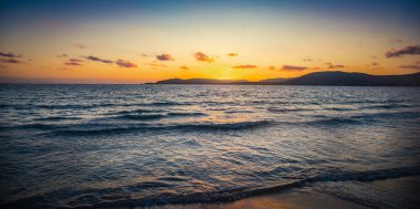 Gün batımında Alghero sahilinde küçük dalgalar. Sardunya, İtalya