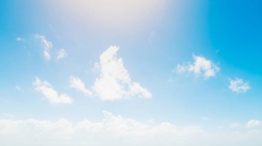 Mavi gökyüzünde beyaz, yumuşak bulutlarla parlayan SUN