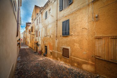 Bulutlu bir günde Alghero 'nun eski kasabasında dar bir sokak. Sardunya, İtalya