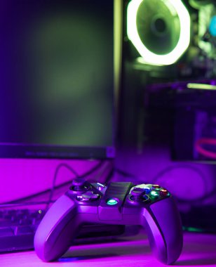 Ahşap bir masada rgb ışıklandırması olan bir oyun kumandası ve cam bilgisayar kılıfını kapat