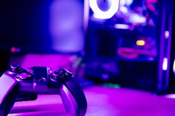 Close up of a game pad and a glass pc case with purple lighting