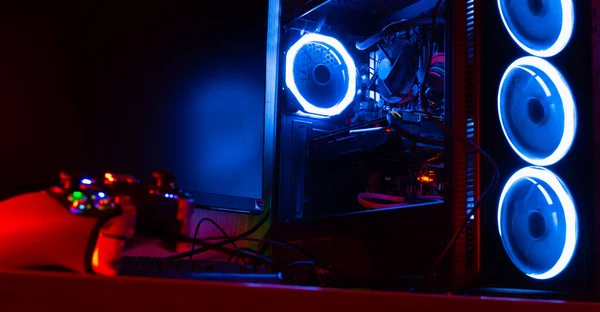 Glass pc case with blue lighting with a game pad on the foreground