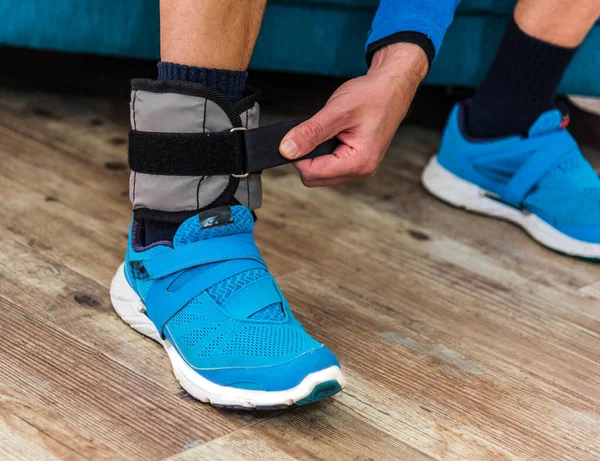 Man closing velcro strap on ankle weight during home workout
