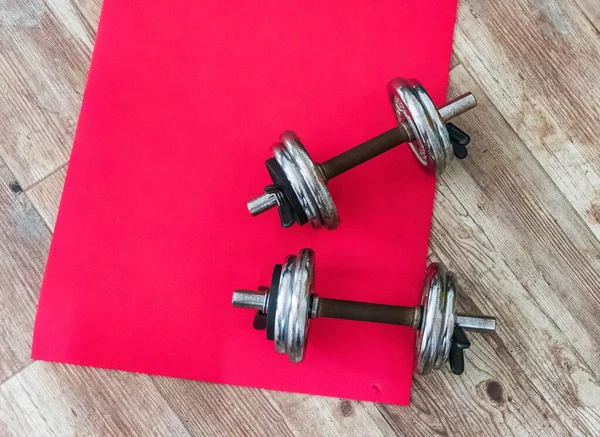 Dumbbells and gym matress on a house floor seen from above