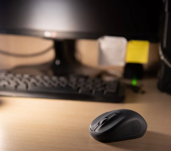 Close up of a computer mouse with keyboard and monitor on the background