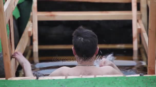 Mann badet am Dreikönigstag in kaltem Eisloch — Stockvideo
