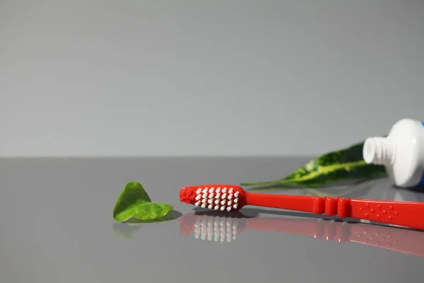 Tubo de escova de dentes de pasta de dentes com folhas verdes — Fotografia de Stock