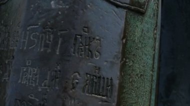 Bilinmeyen eski bir dilde yazılmış, zırhlı bir şövalyenin zırhlı resminin olduğu kalkanın rahatlatılması, bronz topun yakın görüntüsü, hareket halindeki kamera.