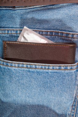 Kahverengi cüzdan ve gri prezervatif kot pantolonun cebine.