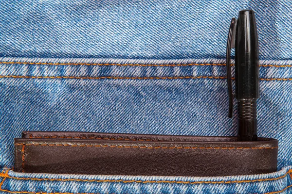 棕色皮夹和黑笔放在蓝色牛仔裤口袋里 — 图库照片