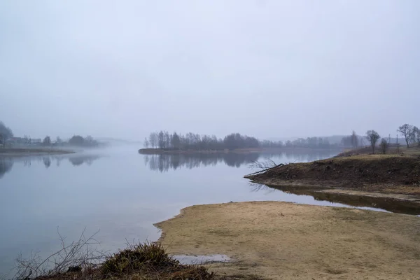 Abandoned place landscape, early morning fog. Calm water, misty lake background.