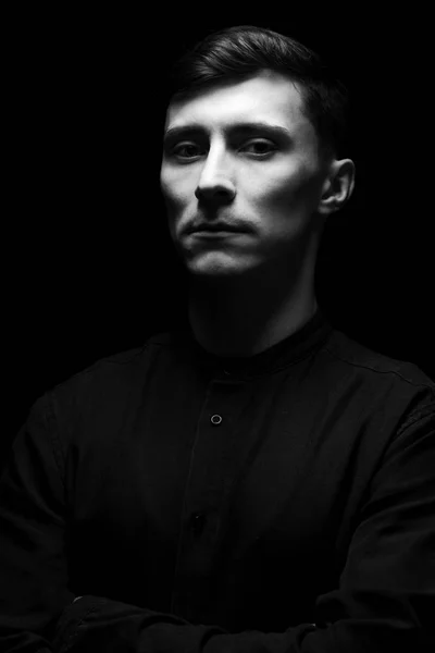 Baixo retrato chave de um homem em camisa preta em preto e branco . — Fotografia de Stock
