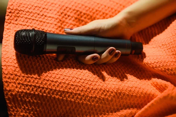 Mikrofon kadın el karşı ve müzik notlar renkli ışık arka plan bulanıklık — Stok fotoğraf