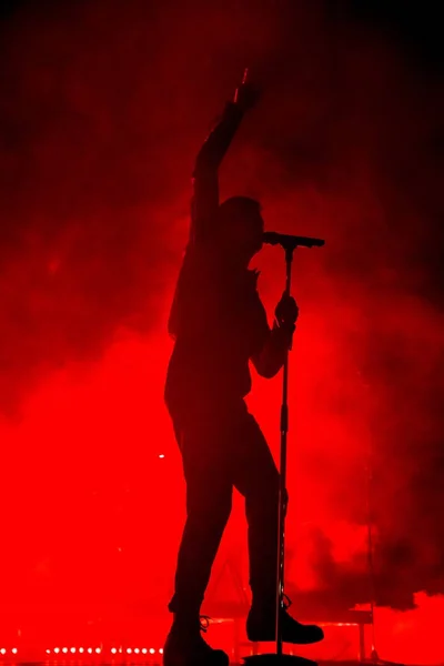 Singer / vocalist performing on stage at a concert in the fog. Dark background, smoke, concert red spotlights. — Stock Photo, Image