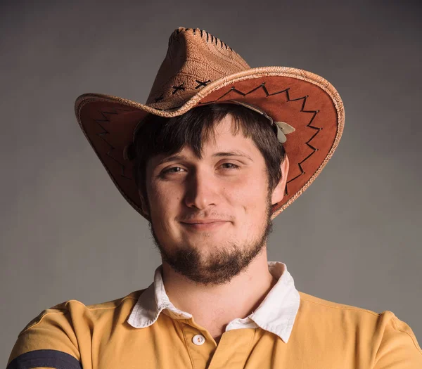 Portret wielki człowiek w kowbojski kapelusz i żółtą koszulkę. Smail młodego człowieka. Strzał studio szary ściany. — Zdjęcie stockowe