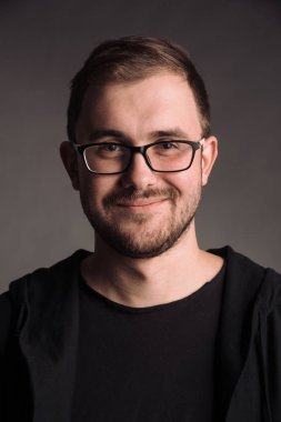siyah t-shirt gri studio arka planda kameraya poz izole erkekte gülümseyen portresi