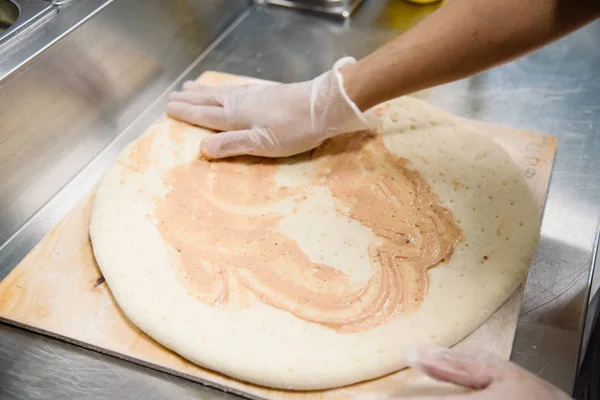 Kvinna händer i latex handskar att göra, dekorera, förbereda pizza. — Stockfoto