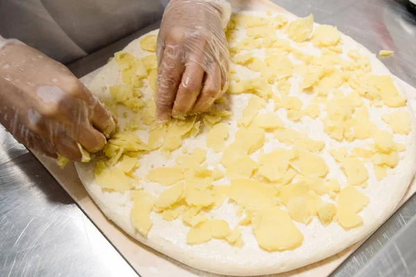 Kvinna händer i latex handskar att göra, dekorera, förbereda pizza. — Stockfoto