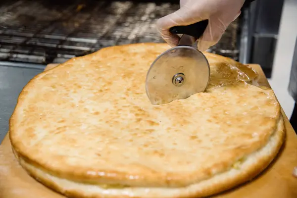 Processen för matlagning och skära pizza. Närbild. Restaurang, café eller pizzeria rätter — Stockfoto