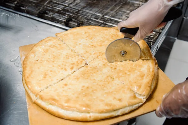 Processen för matlagning och skära pizza. Närbild. Restaurang, café eller pizzeria rätter — Stockfoto