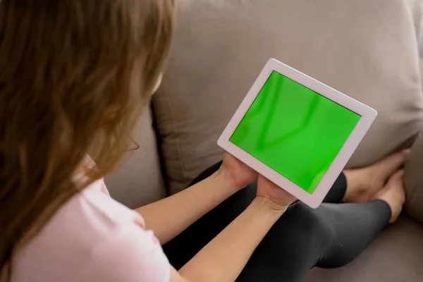 Evde kanepede oturan ve dijital tablet bilgisayar seyir ile yeşil perde çekici genç kadın portresi