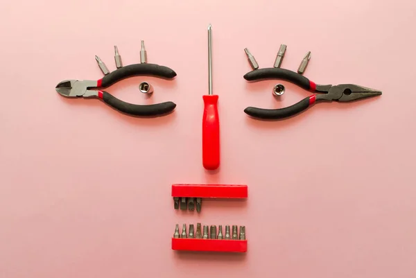 Conceptual set of tools on pink background. It looks like a woman face. Working handmade instruments. Top view. — Stock Photo, Image