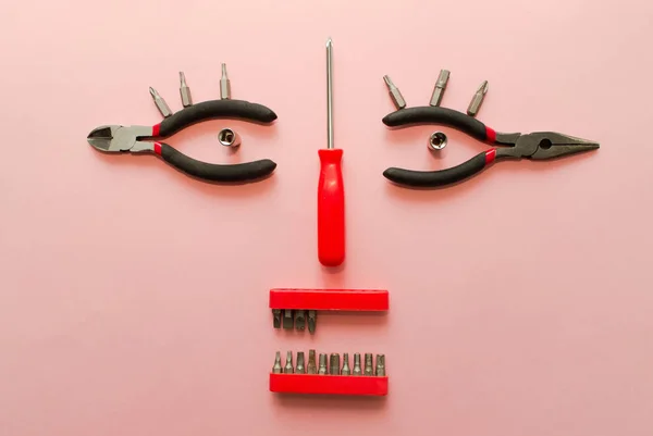 Kavramsal pembe bir arka plan üzerinde araçlar kümesi. Bir kadın yüzü gibi görünüyor. El yapımı araçlar çalışma. Üstten Görünüm.