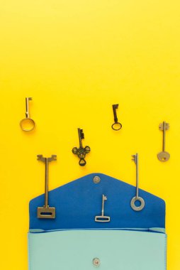 Bir sürü eski anahtarları kopya alanı, üstten görünüm ile renkli arka plan üzerinde şirin çanta dışarı açık düz yatırın.