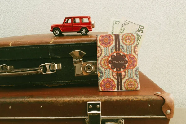 Part of vintage leather travel valises or old suitcase with passport, money and toy car. Close up