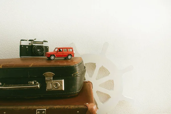 Part of leather travel valises or old suitcase with camera, red toy car and vintage white steering wheel . Close up