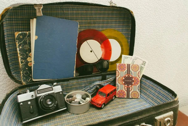 Abra valises de viagem de couro ou mala velha com câmera, carro de brinquedo, discos de vinil vintage, passaporte, dinheiro, óculos de sol e livros antigos Close up, foto de viagem — Fotografia de Stock