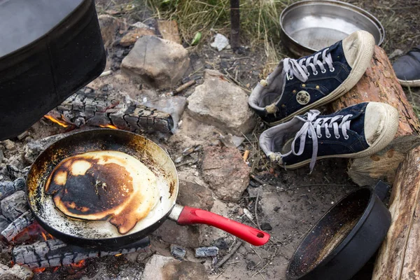 Panqueque cocido al fuego en una sartén con una pluma roja . — Foto de Stock