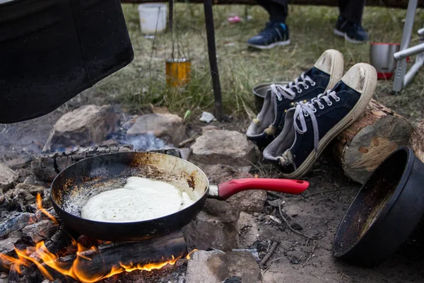 Panqueque cocido al fuego en una sartén con una pluma roja . —  Fotos de Stock