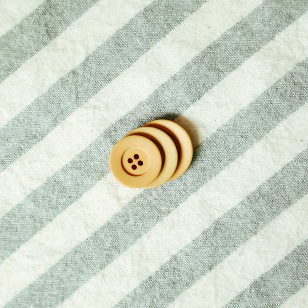 Botón simple beige sobre fondo de tela de patrón de rayas — Foto de Stock