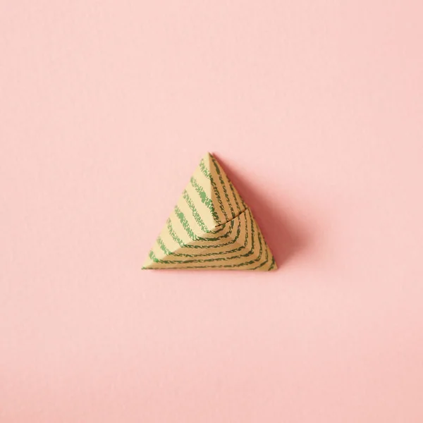 Pirámide triángulo forma papel sobre fondo rosa — Foto de Stock