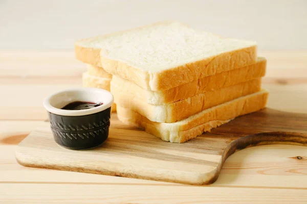 sliced plain bread and jam on wooden tray