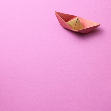 Pembe zemin üzerinde kağıt gemi