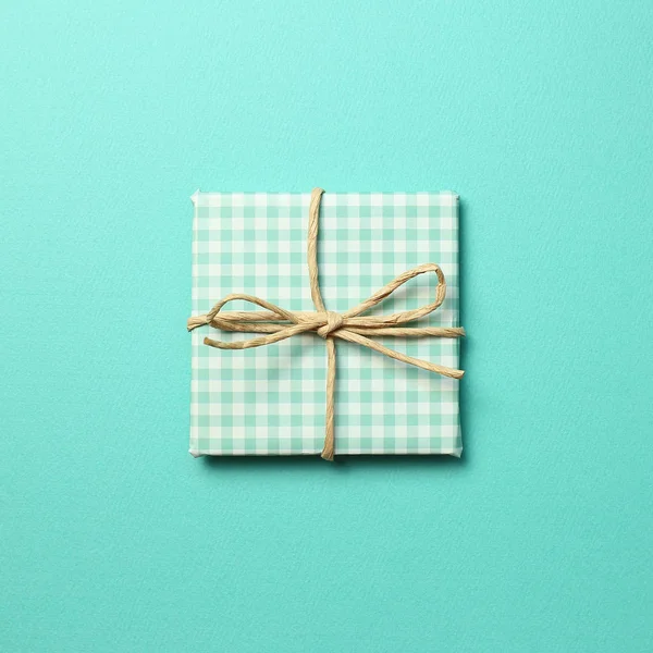 Green gift box on mint green background. Christmas or birthday, anniversary concept