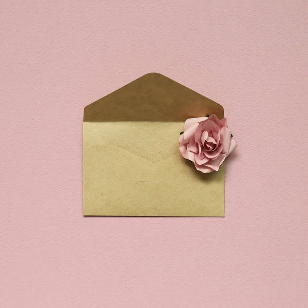 Sobre de papel marrón kraft con rosa rosa sobre fondo rosa — Foto de Stock