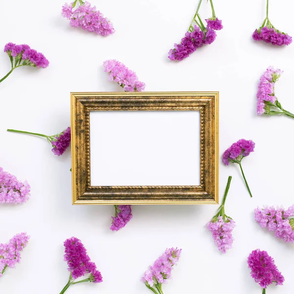Antique picture frame with pink purple statice flowers on white background. Floral composition, flat lay, top view, copy space