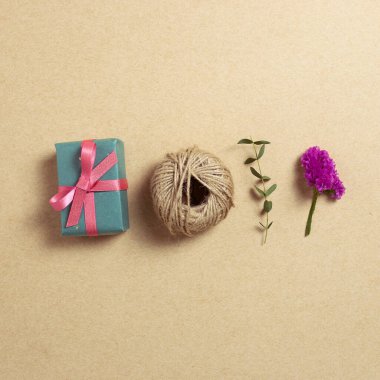 Kraft kağıt arka planında kuru çiçekli hediye kutusu ve ip. Düz konum, üst görünüm, kopyalama alanı