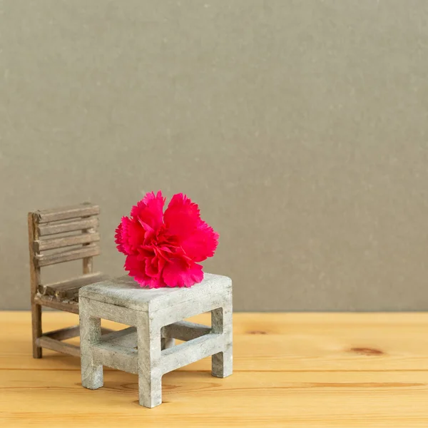 Pink spray carnation flower on school desk with empty chair. Teacher\'s day concept, copy space