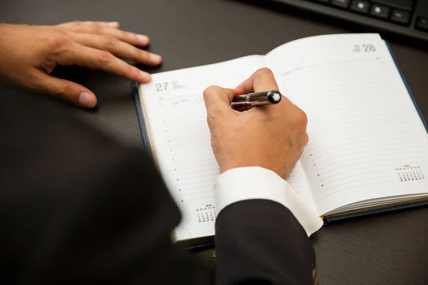 Empresário escrevendo notas ser caneta em um caderno — Fotografia de Stock