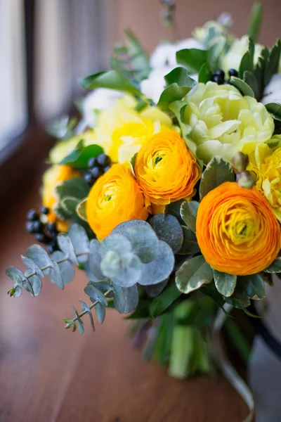 A large beautiful bouquet of cotton, eucalyptus, tulips, roses of beautiful yellow, orange and white colors on a wooden background. Holiday gift concept, mother\'s day, birthday, wedding