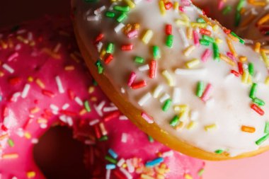 İki sulu taze tatlı çörek, üzerine şeker kreması ve pembe bir arka plan serpiştirilmiş.