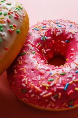 İki sulu taze tatlı çörek, üzerine şeker kreması ve pembe bir arka plan serpiştirilmiş.