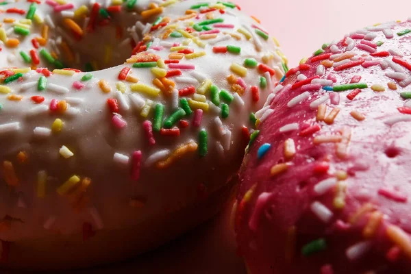 İki sulu taze tatlı çörek, üzerine şeker kreması ve pembe bir arka plan serpiştirilmiş.