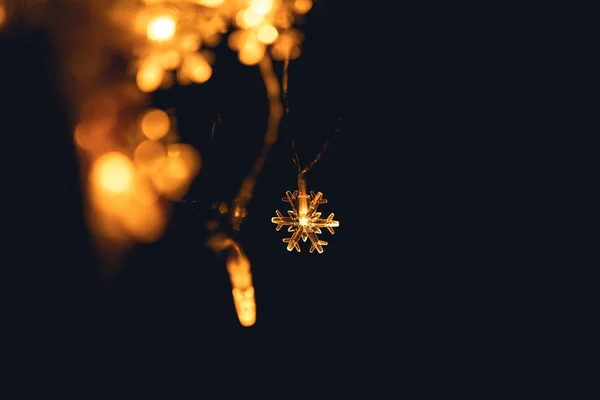 Invierno - Una pequeña luz en forma de copo de nieve naranja en la noche —  Fotos de Stock